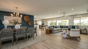 A spacious living room with a dining area, a sofa set, and a chandelier.