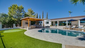 A modern house with a swimming pool, outdoor seating, and a covered patio.