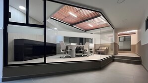 Un espacio de oficina moderno con un panel de vidrio, una mesa de conferencias y sillas de oficina.