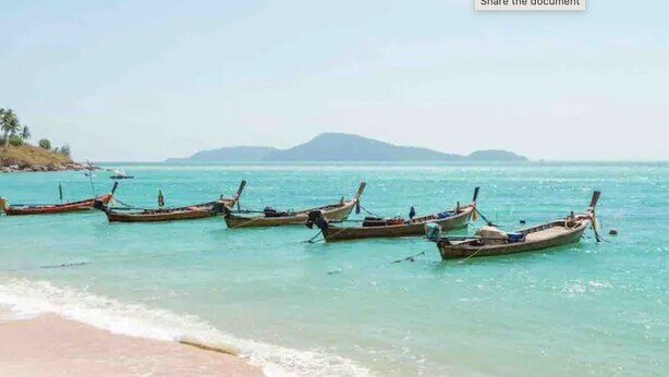 A beach with several traditional boats anchored in the water.