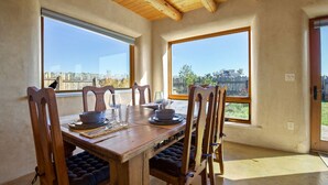Un espace repas avec une table et des chaises en bois, de grandes fenêtres offrant une vue sur le paysage urbain et un plafond en bois.