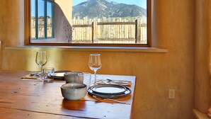 Une table à manger avec vue sur les montagnes, visible par une fenêtre.