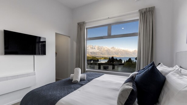 Une chambre d’hôtel moderne dotée d’une grande fenêtre donnant sur les montagnes.