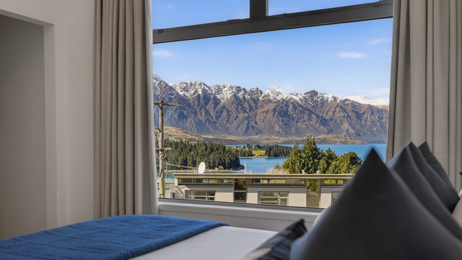 Un dormitorio con un ventanal grande que da a un paisaje montañoso y un lago.