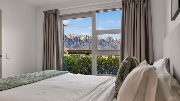 Une chambre d’hôtel avec un lit, des rideaux et une fenêtre donnant sur la montagne.