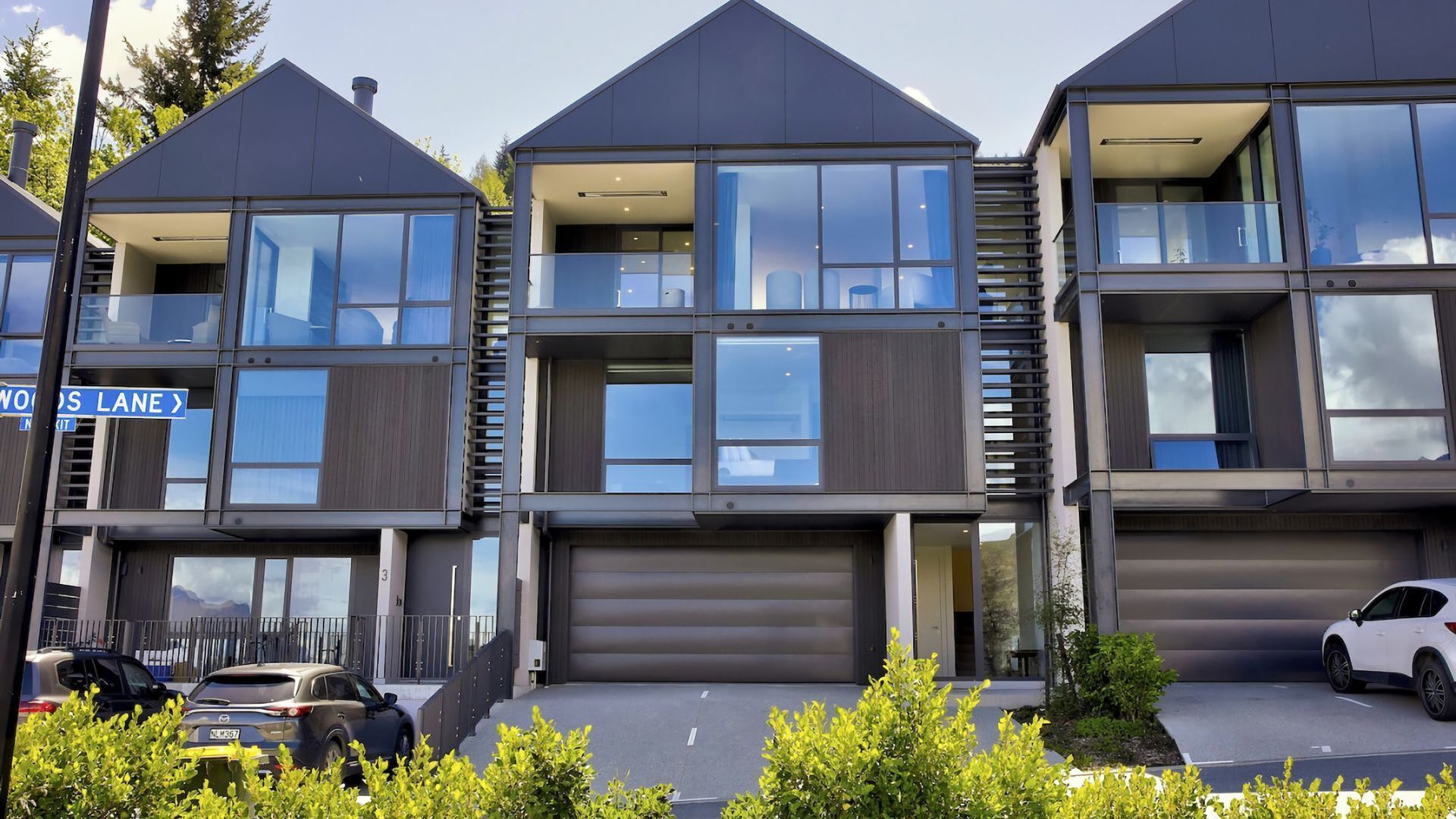 Een modern woongebouw met meerdere appartementen, grote ramen en een garage.