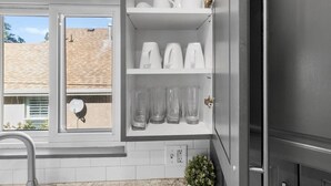 Una cocina con armarios blancos, un ventanal y una planta.