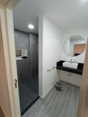 A bathroom with a shower, a sink, and a mirror.