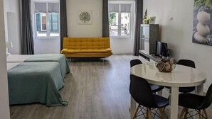 A modern living room with a sofa, a dining table with chairs, and a television. - Tanoeiros Studios (Funchal)