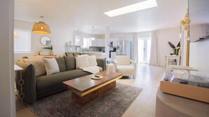 A modern living room with a sofa, coffee table, and a dining area.
