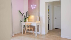 A white desk with a neon sign reading "Bohemian Chic" in a room with light wooden flooring and a door in the background.