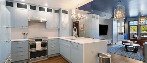 A modern kitchen with built-in appliances, a central island, and a dining area with a view.