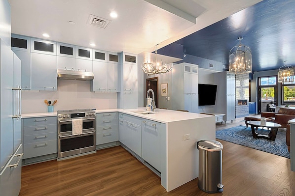 A modern kitchen with built-in appliances, a central island, and a dining area with a view.