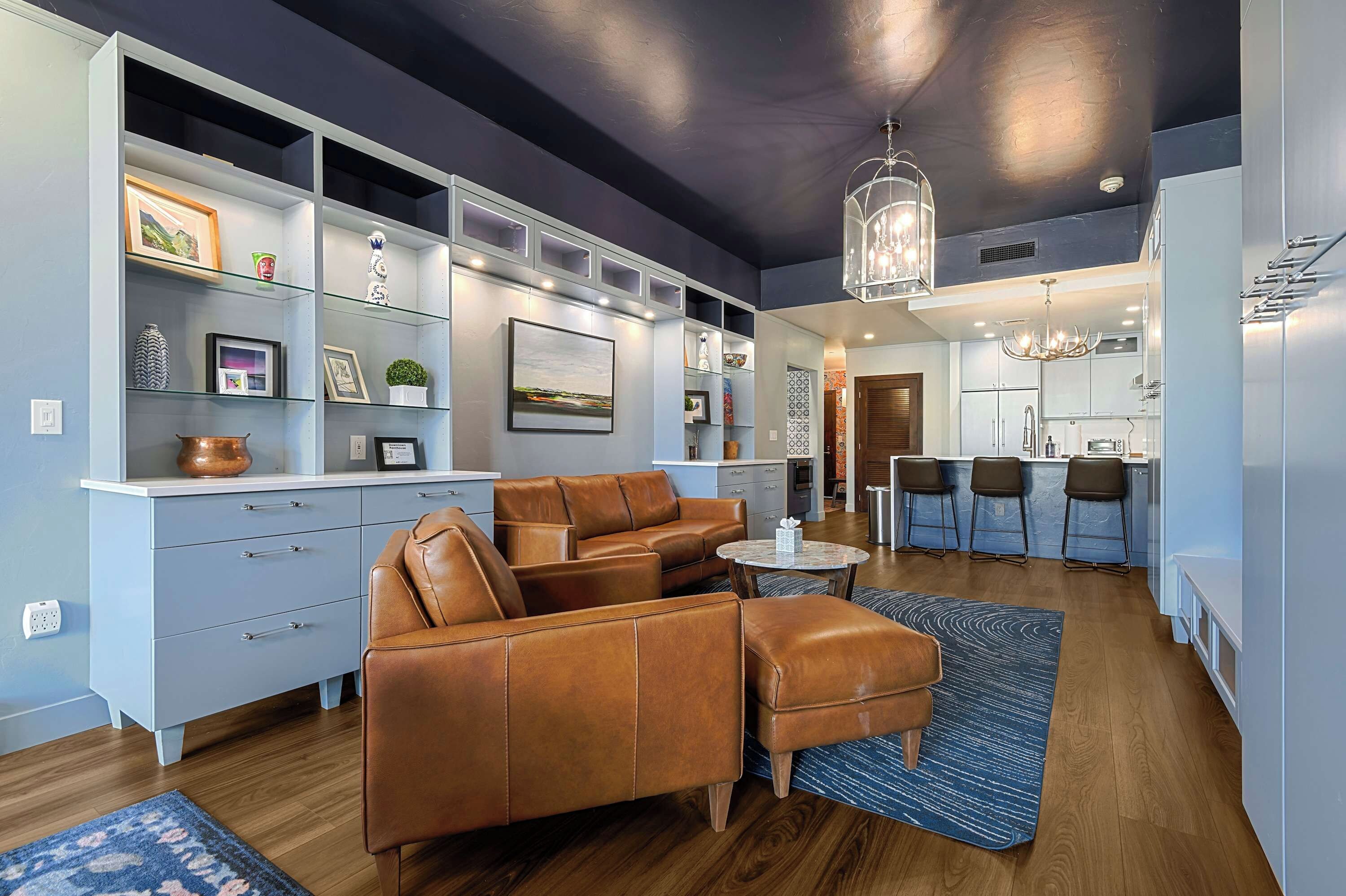 A modern living room with a leather sofa, a coffee table, and a bookshelf filled with decorative items.