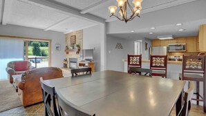 Un vaste espace dédié à la salle à manger, avec une grande table et des chaises, un lustre et une vue sur l’extérieur grâce à une porte-fenêtre coulissante.