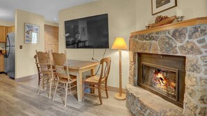A dining area with a stone fireplace, a table, and chairs. - Pines Peak Place Summ (Steamboat Springs)