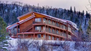 A multi-story wooden lodge with balconies, surrounded by snow-covered trees.