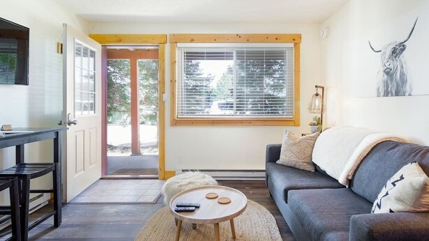 A living room with a sofa, a coffee table, a TV, and a window with blinds.
