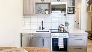 A modern kitchen with stainless steel appliances, wooden cabinets, and a white tiled backsplash. - Sunset Retreat (Steamboat Springs)