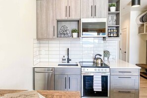 A modern kitchen with stainless steel appliances, wooden cabinets, and a white tiled backsplash. - Sunset Retreat (Steamboat Springs)