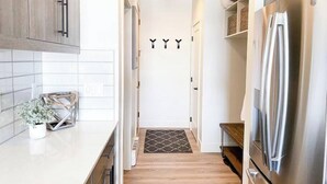 A narrow kitchen with wooden cabinets, a stainless steel refrigerator, and a tiled backsplash. - Sunset Retreat (Steamboat Springs)