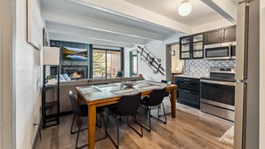 Een moderne keuken met een eethoek, houten vloeren en inbouwapparatuur.