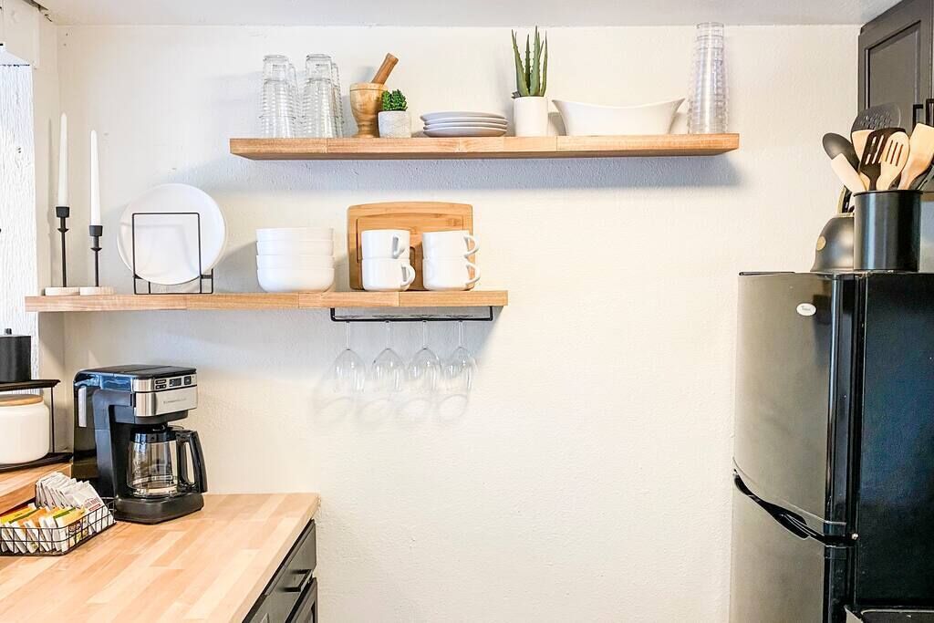 Eine Küche mit Holzböden, die Geschirr, Gläser und eine Kaffeemaschine beherbergt.