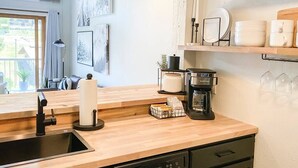 Een moderne keuken met een houten aanrecht, een koffiezetapparaat en een spoelbak.