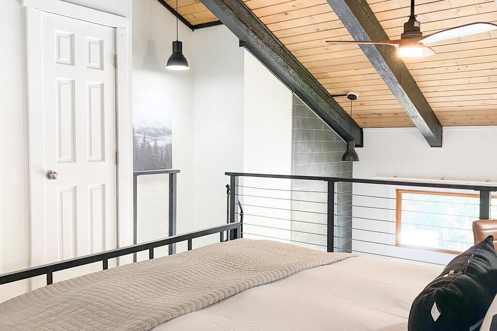 Un dormitorio con cama, ventana, puerta y ventilador de techo.