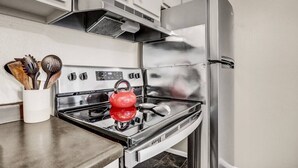 Une cuisine équipée d’appareils électroménagers en acier inoxydable, notamment une cuisinière et un réfrigérateur.