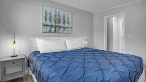 Ein Schlafzimmer mit einem Bett, Nachttischen und einem Gemälde an der Wand.