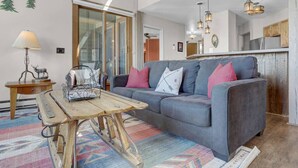 A modern living room with a grey sofa, colorful rug, and a wooden coffee table. - Rustic Ridgetop Retreat (Steamboat Springs)