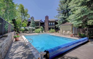 A rectangular pool with a blue edge, surrounded by lounge chairs and potted plants.