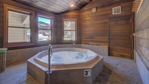 A wooden cabin with a hot tub, large windows, and a door. - Rustic Ridgetop Retreat (Steamboat Springs)
