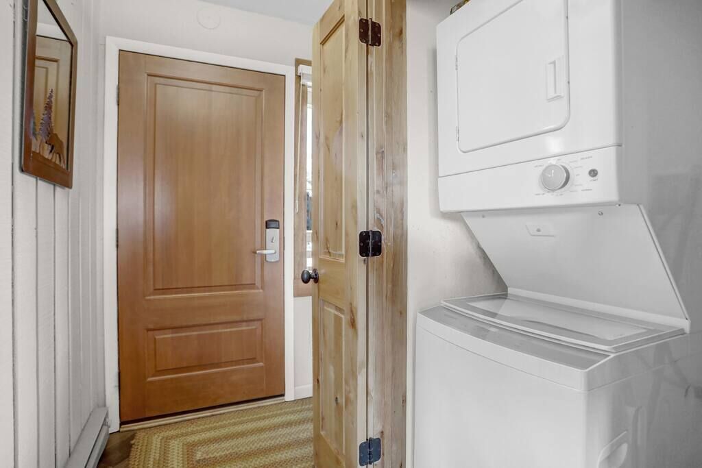 Une pièce avec une porte en bois, un lave-linge blanc et une petite fenêtre.
