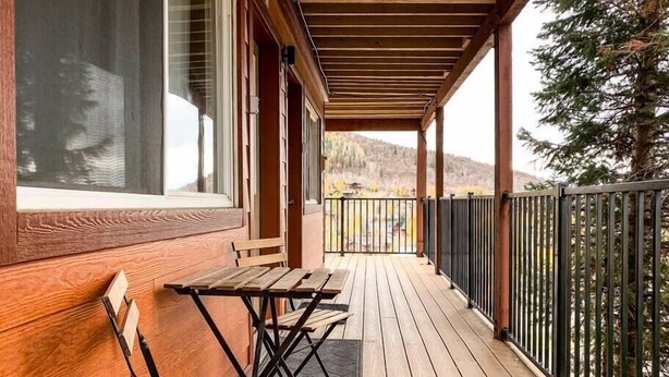 A wooden deck with a table and bench, a metal railing, and a view of a mountainous landscape. - Aspen Vista Hideaway (Steamboat Springs)