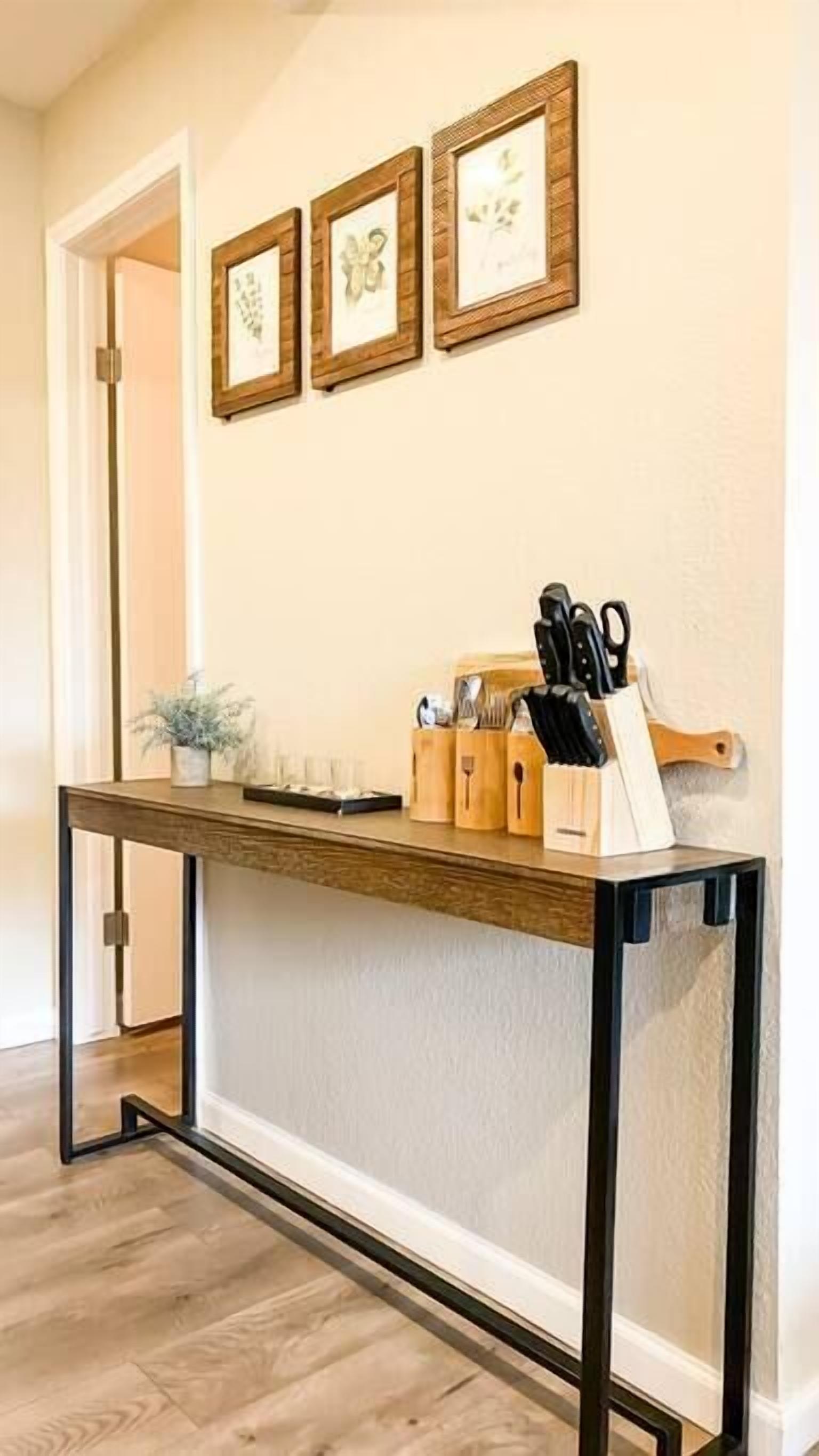 A kitchen area with a wooden countertop, a knife block, and framed artwork on the wall.