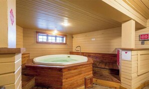 Una sauna de fusta amb una banyera d'hidromassatge, una finestra i un senyal que indica que la banyera d'hidromassatge està apagada.