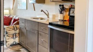 Cocina compacta con electrodomésticos de acero inoxidable, un lavabo y alacenas.