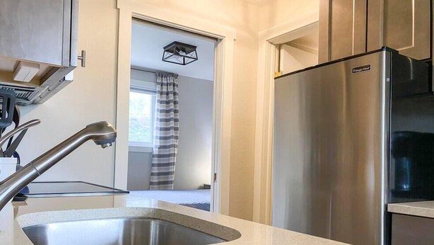 Una cocina con un refrigerador de acero inoxidable, un lavamanos y un grifo moderno.