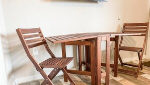 Un juego de comedor de madera con una mesa y dos sillas, un enchufe en la pared y un piso de baldosas.