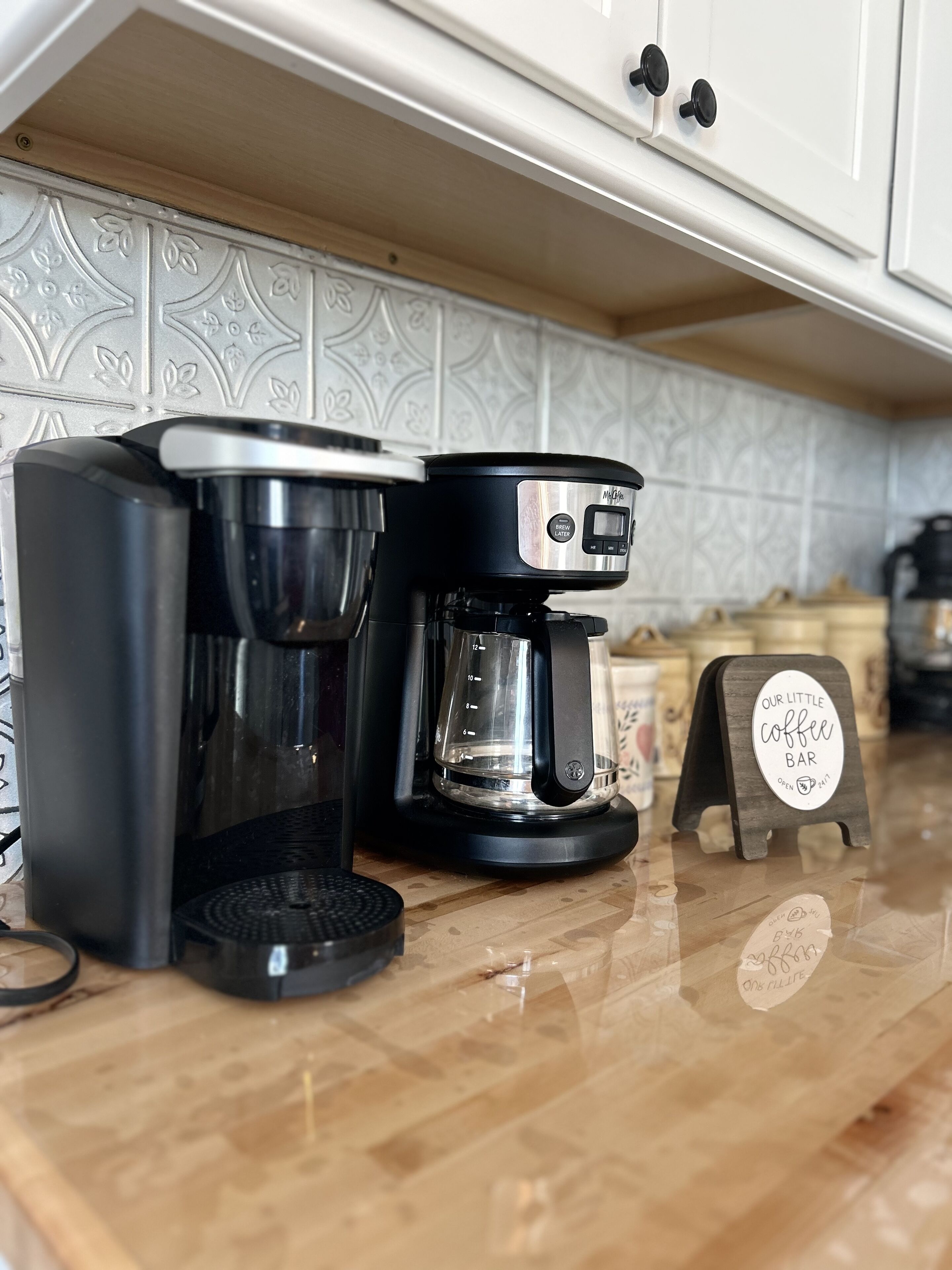 A coffee maker on a kitchen counter with a coffee pot and a scale.