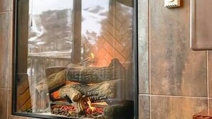 A modern living room with a fireplace, a mounted television, and a cozy seating area. - Slopeside Chalet (Steamboat Springs)