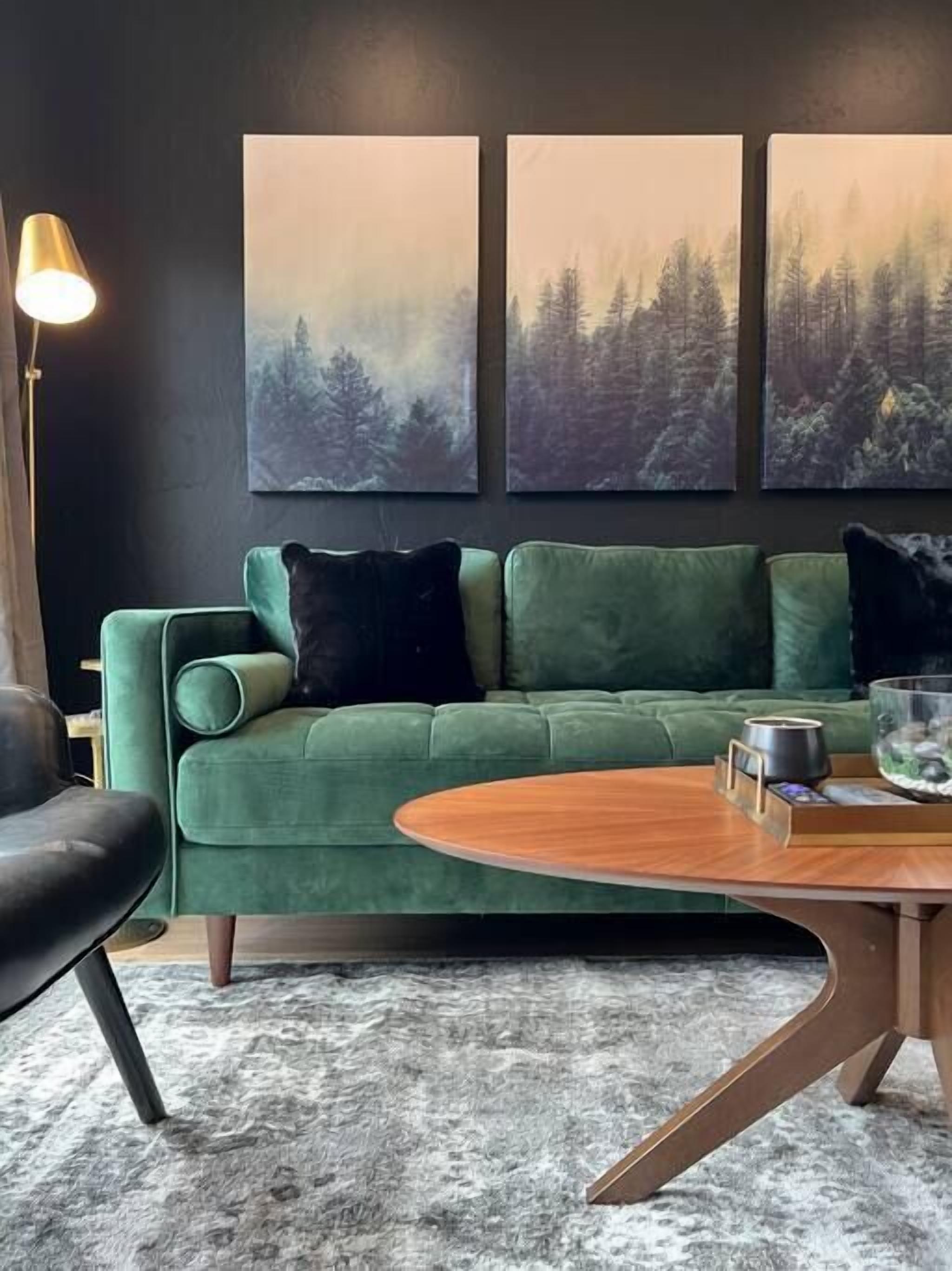 A green sofa with black cushions, a round wooden coffee table, and a floor lamp.