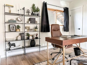 A modern office space with a desk, chair, and a bookshelf filled with books, decorative items, and plants. - Evergreen Escape Summ (Steamboat Springs)