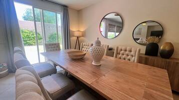 A dining area with a wooden table, cushioned chairs, a decorative vase, and a lamp.