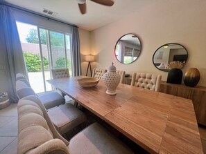 Een eethoek met een houten tafel, zachte stoelen, een decoratieve vaas en een lamp.