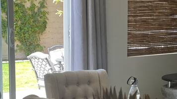 A living room with a beige sofa, a patterned armchair, and a large potted plant.