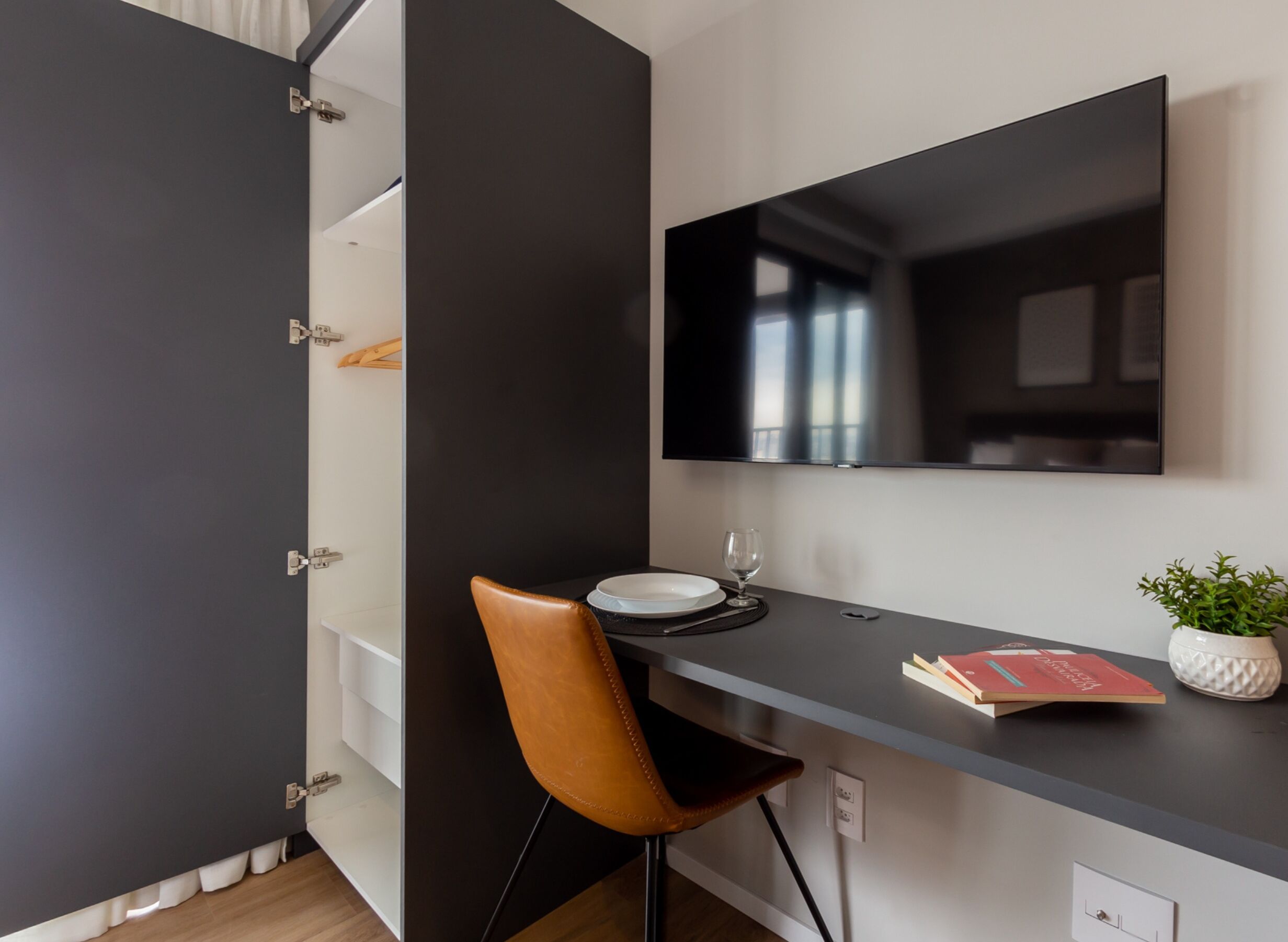 A modern room with a desk, chair, and a flat-screen TV mounted on the wall.