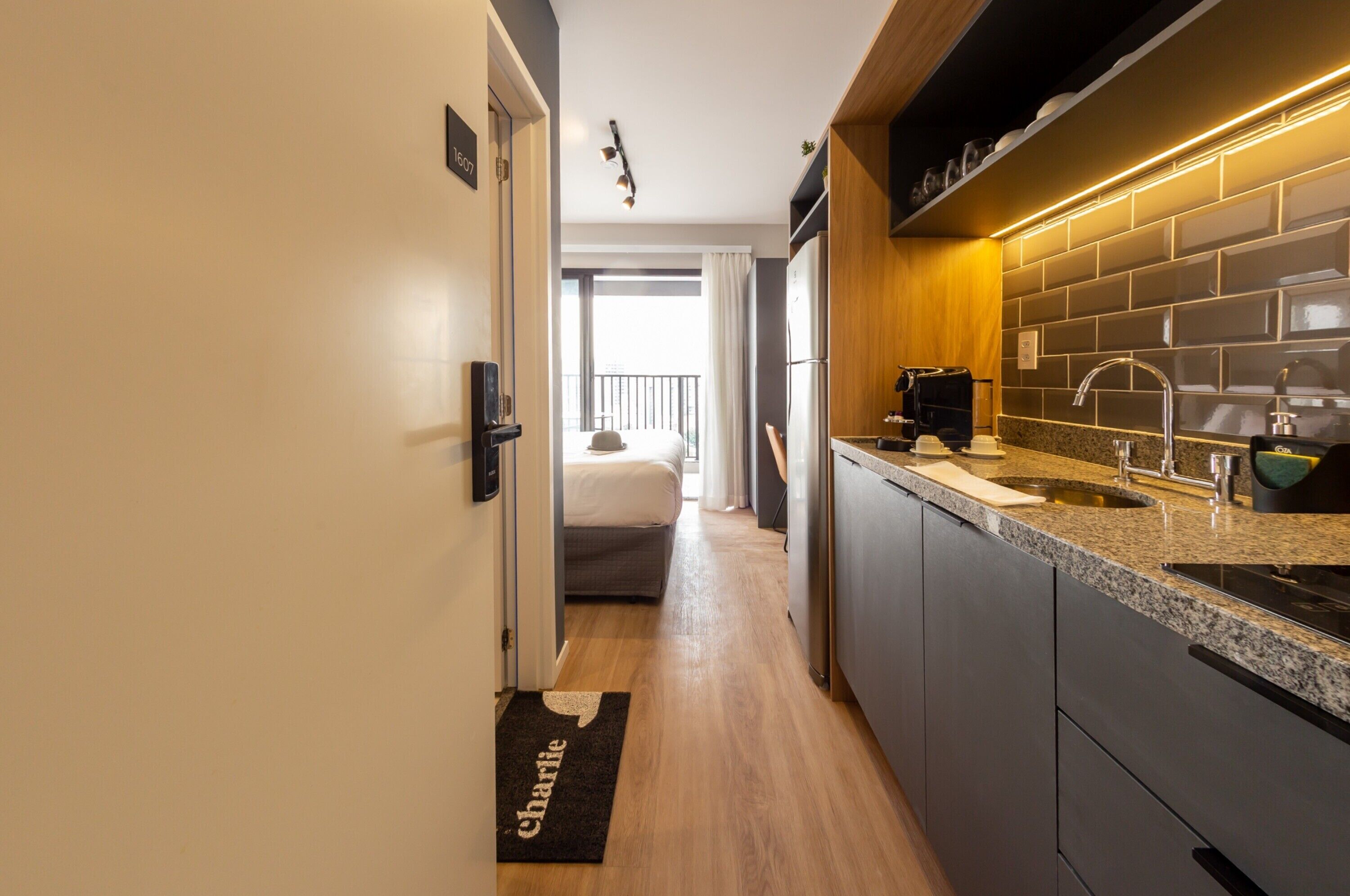 A modern kitchen with a granite countertop, stainless steel appliances, and a black backsplash.